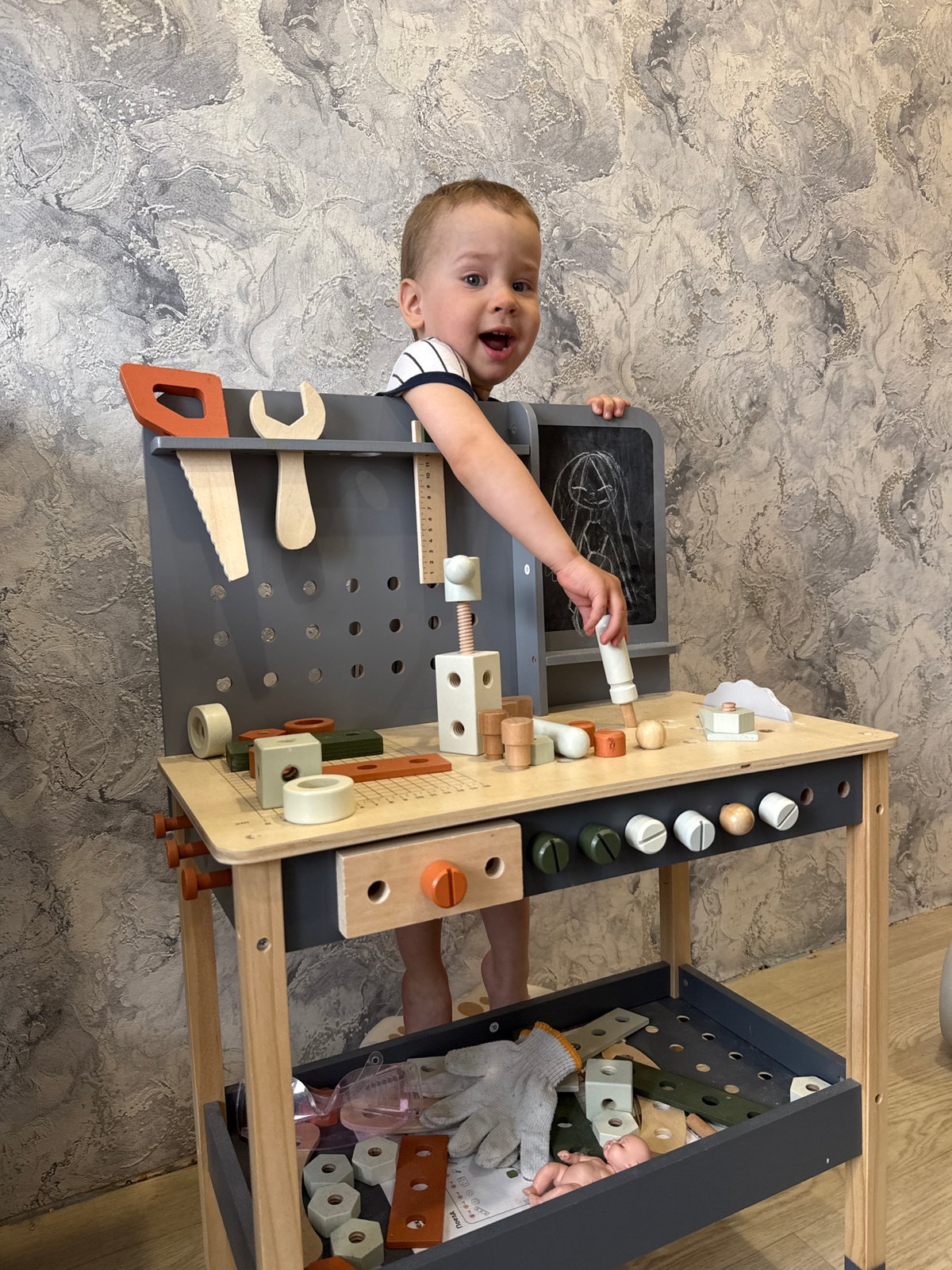 Toddler enjoys playful moments with wooden toy workbench indoors