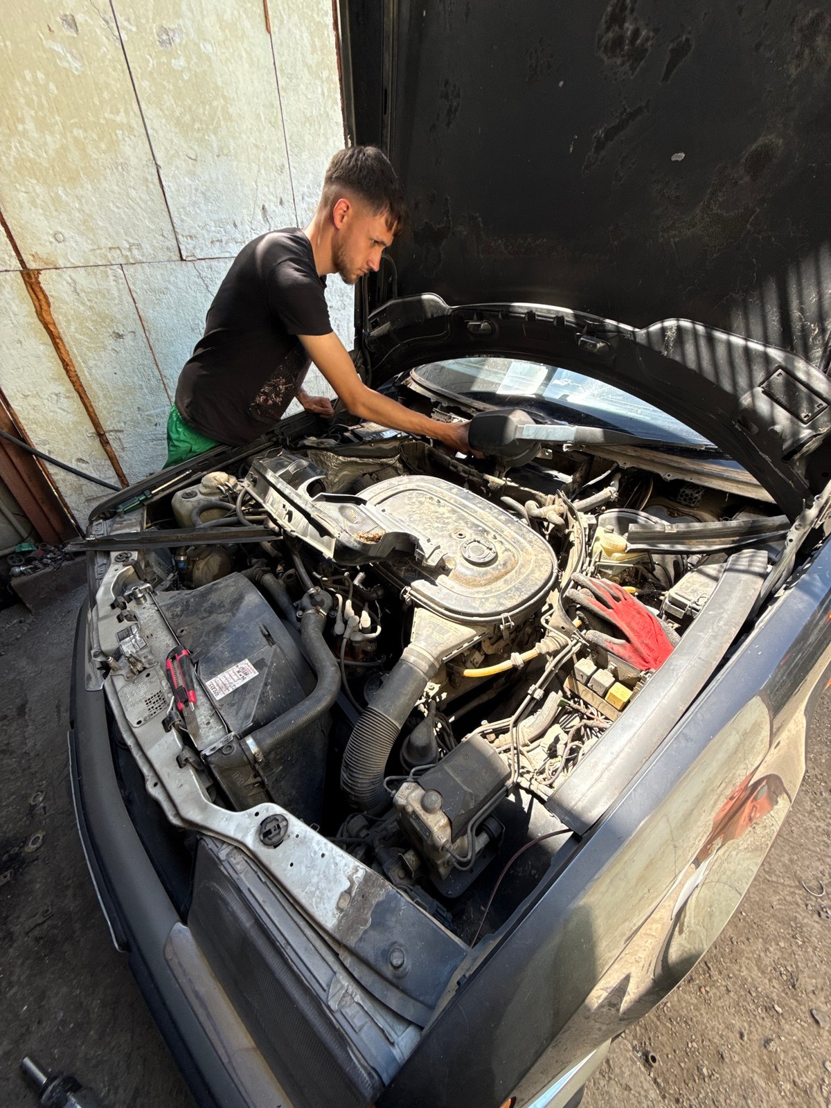 Mechanic works on engines in Bulgarian garage with cat