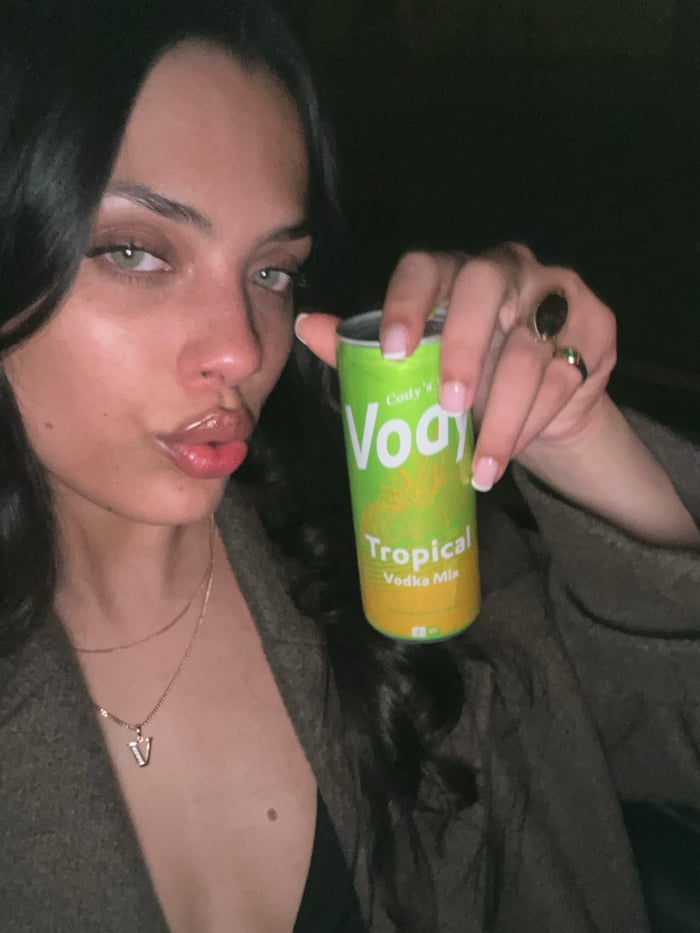 Woman poses with tropical vodka mix drink in Paris selfie