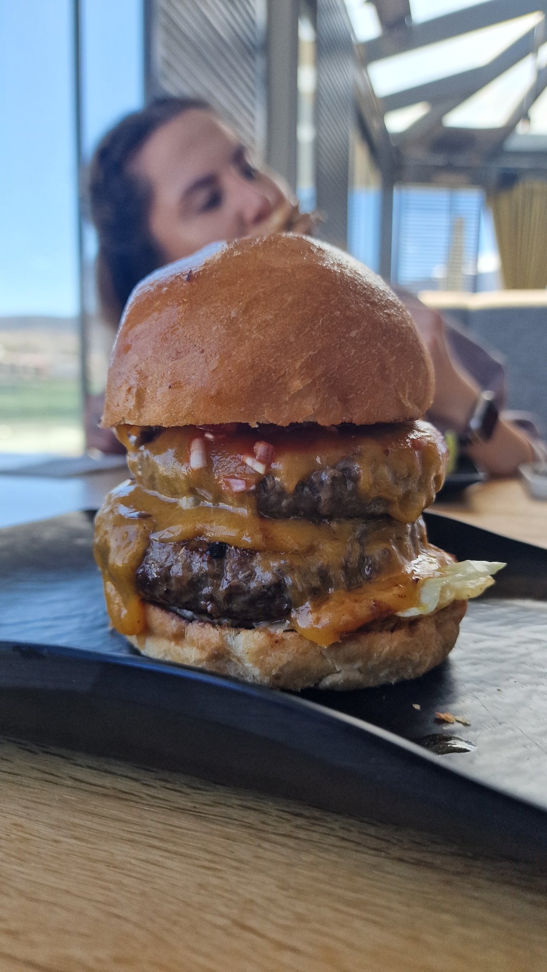 Half-finished double cheeseburger observed on wooden table surface