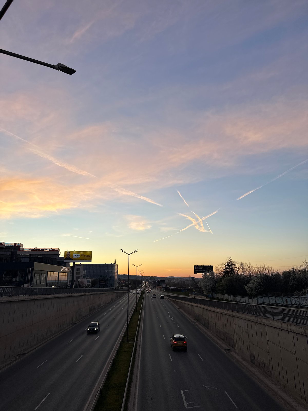 Evening traffic flows on Sofia highway under vapor-streaked sky