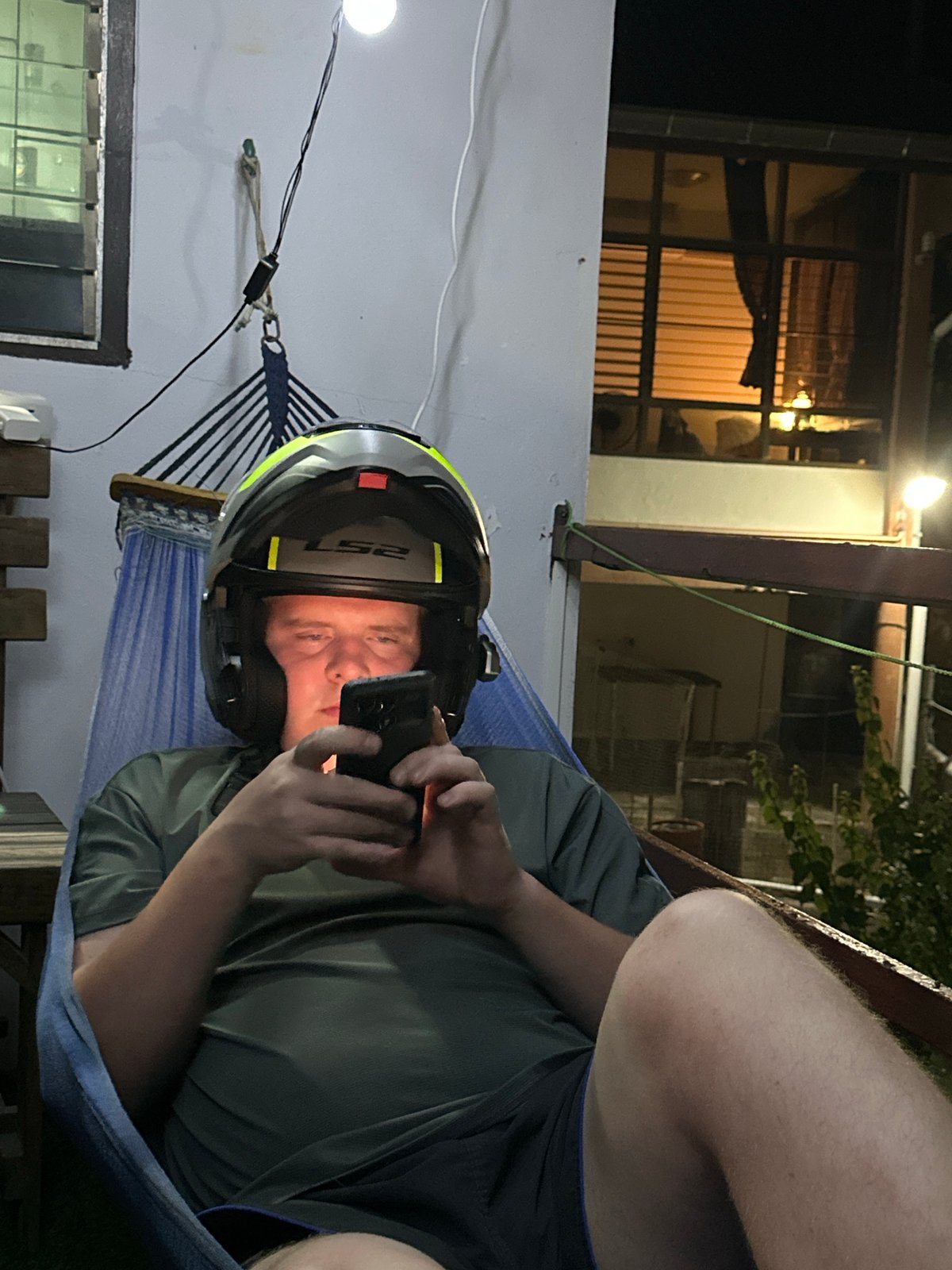 Hammock time in Karon, helmet on, phone in hand.