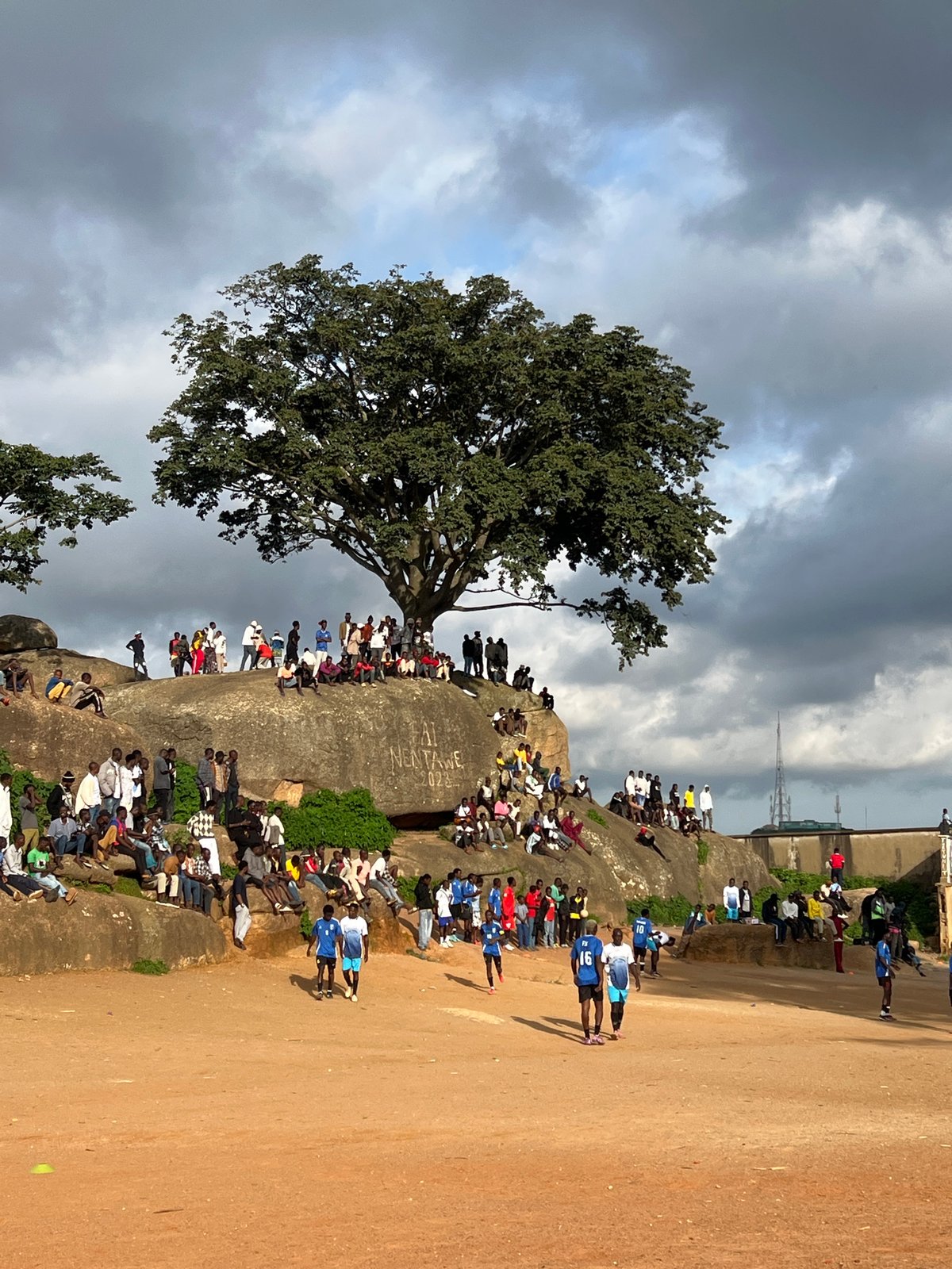 Pickup soccer and community gathering on a dusty field in Jos