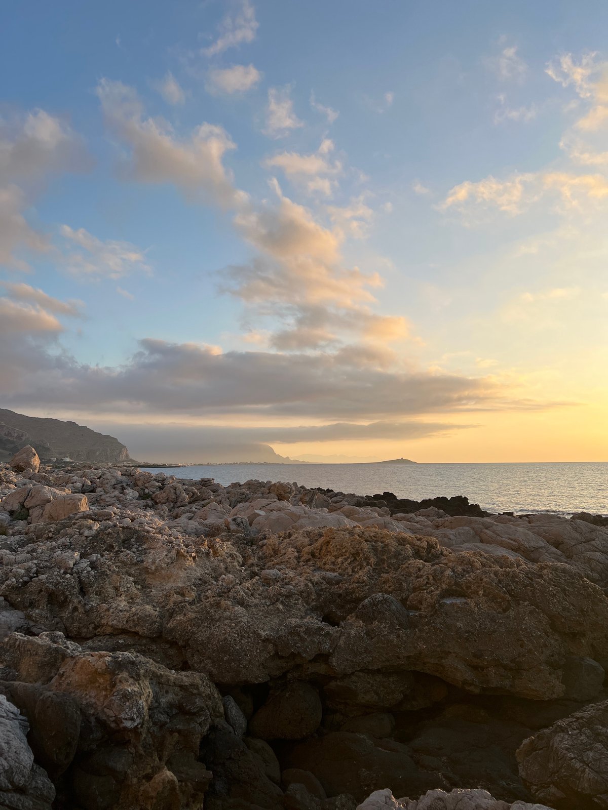 Sunset from Palermo's rocky Mediterranean coastline, crescent moon rising