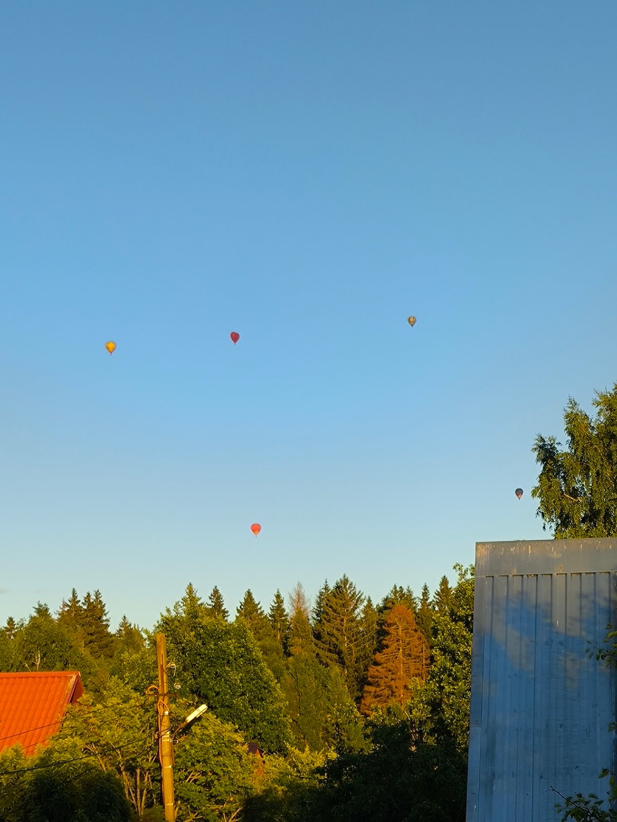 Hot air balloons fill the sky over a Russian village garden