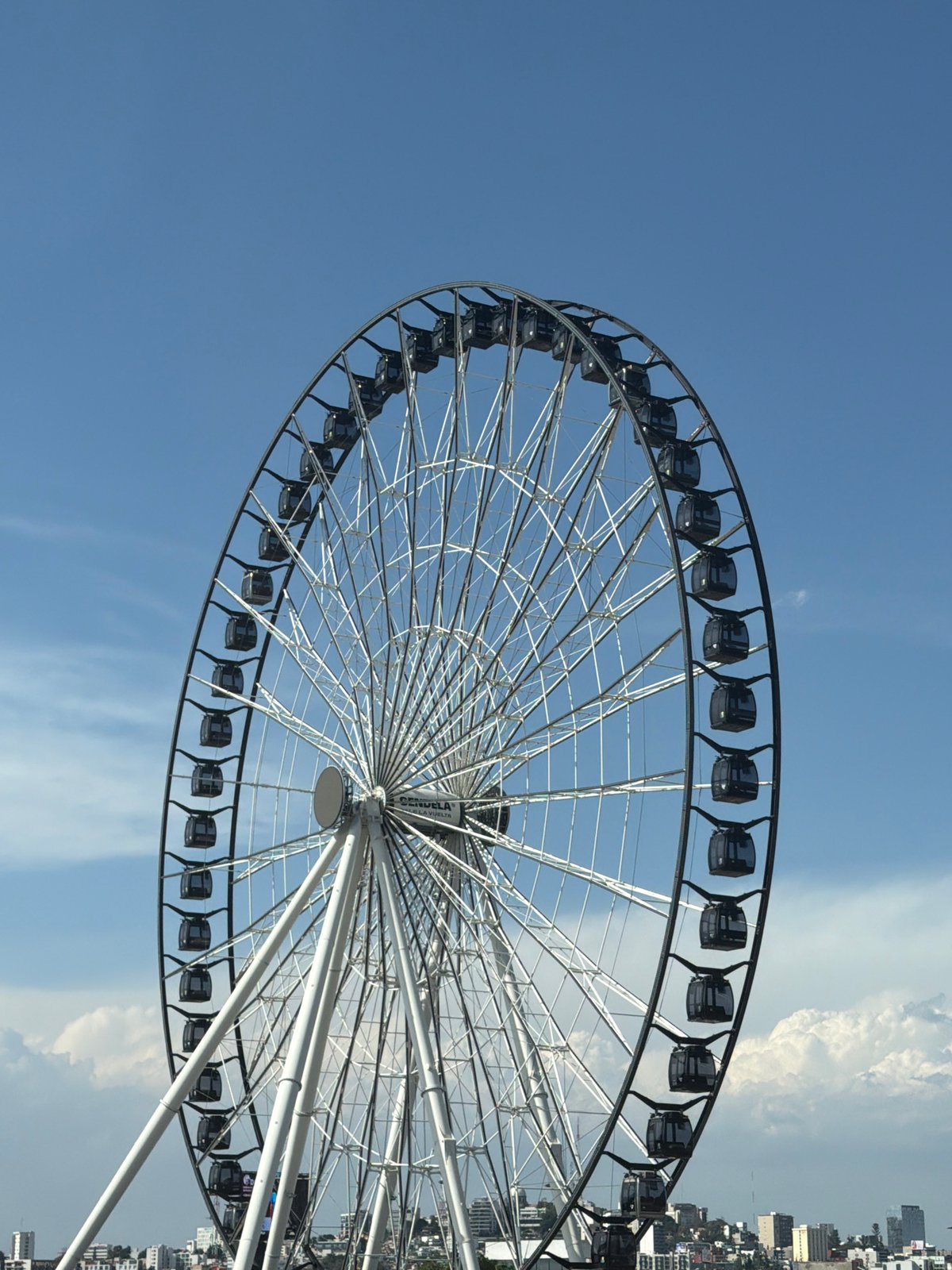 Ferris wheel spotted against blue sky, rotated image captured