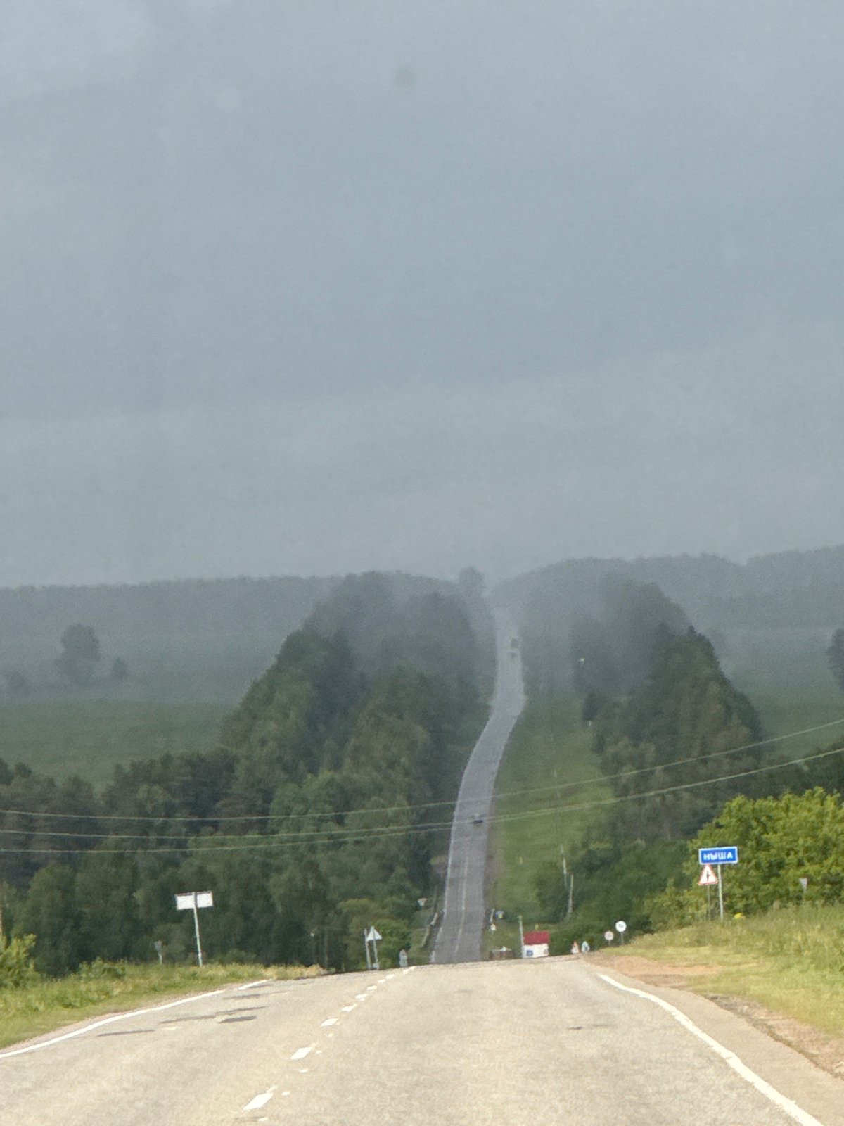 Rural road viewed under overcast skies in Nysha, Russia