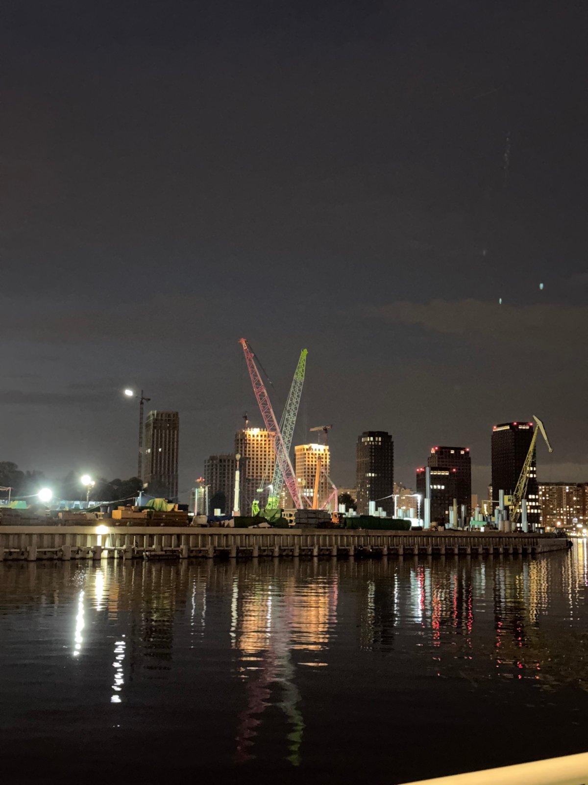 Moscow riverfront at night — cafés, cranes, and reflections