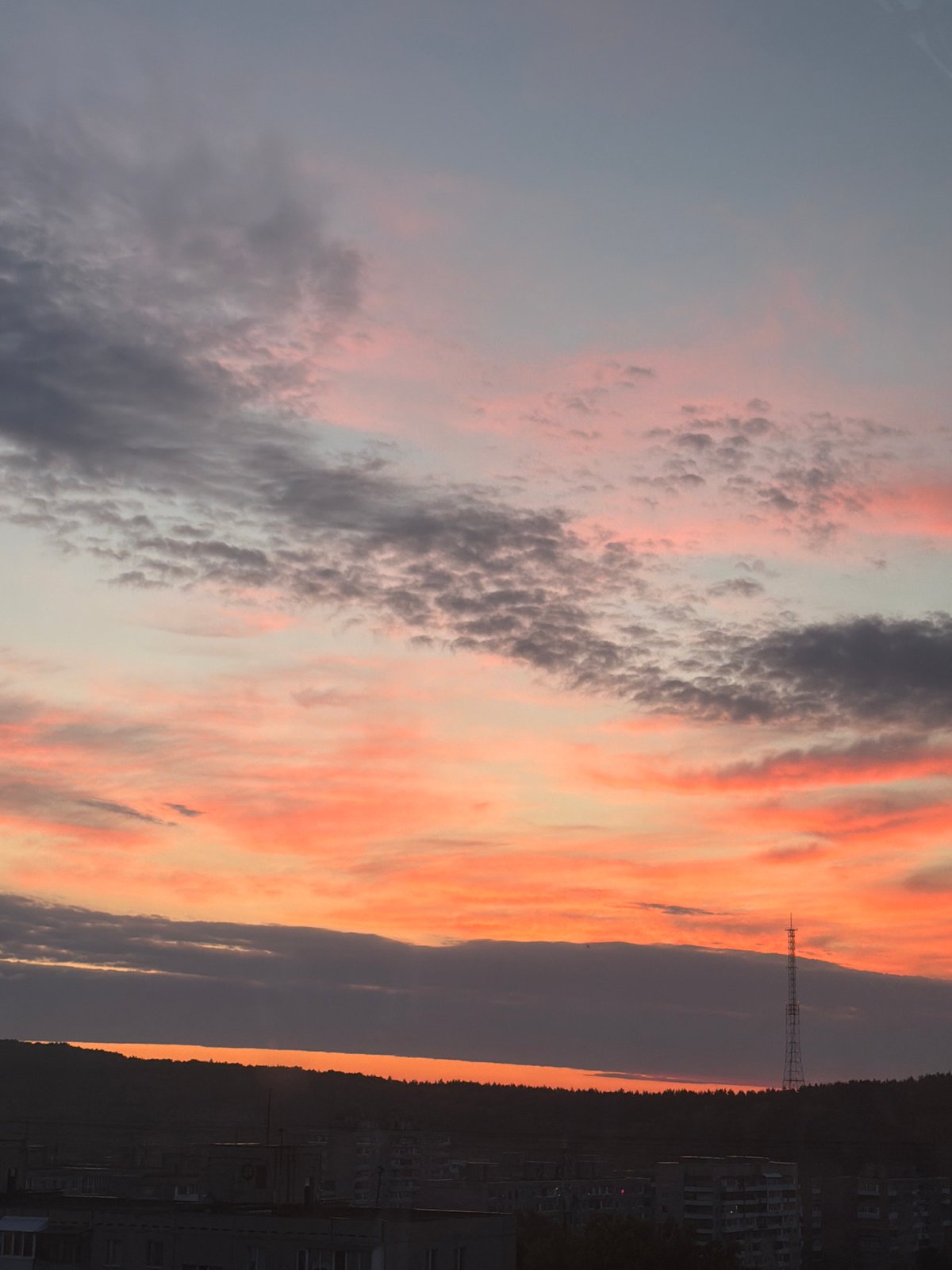 Dramatic sunset illuminates city skyline as witnesses document evening