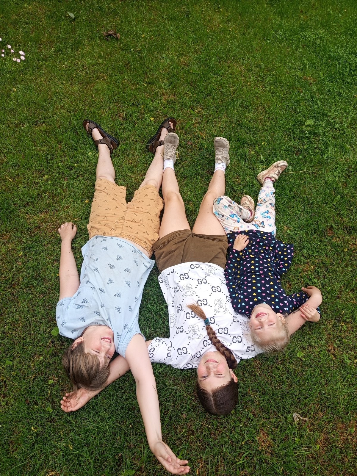 Three people form pinwheel pattern on lawn