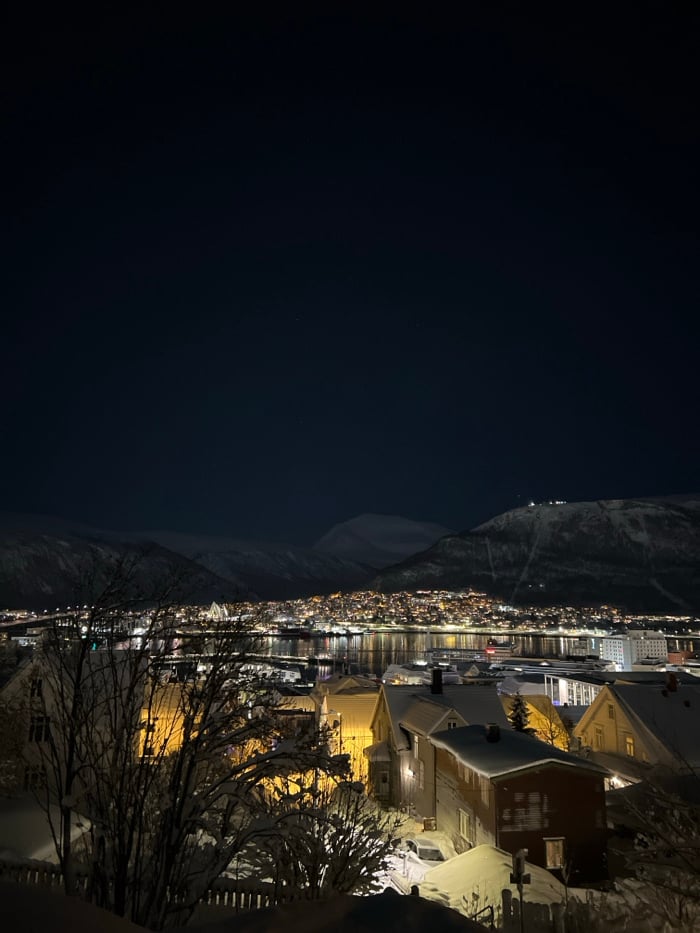 Winter night illuminates snow-covered Tromsø alongside still waters
