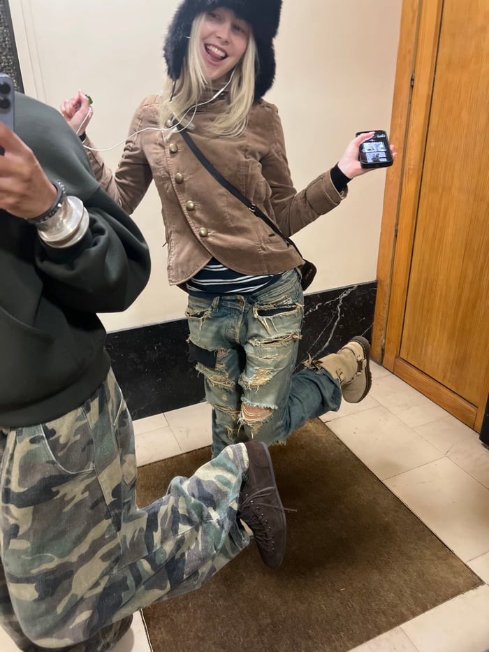 Two people take mirror selfies in Paris hallway
