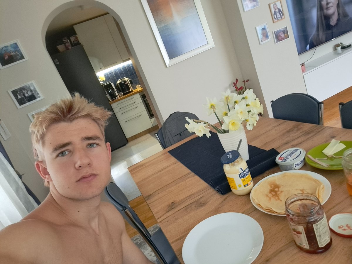 Young man takes shirtless selfie at dining table in Sofia