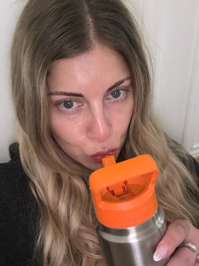 Blonde woman drinks from water bottle in Paris