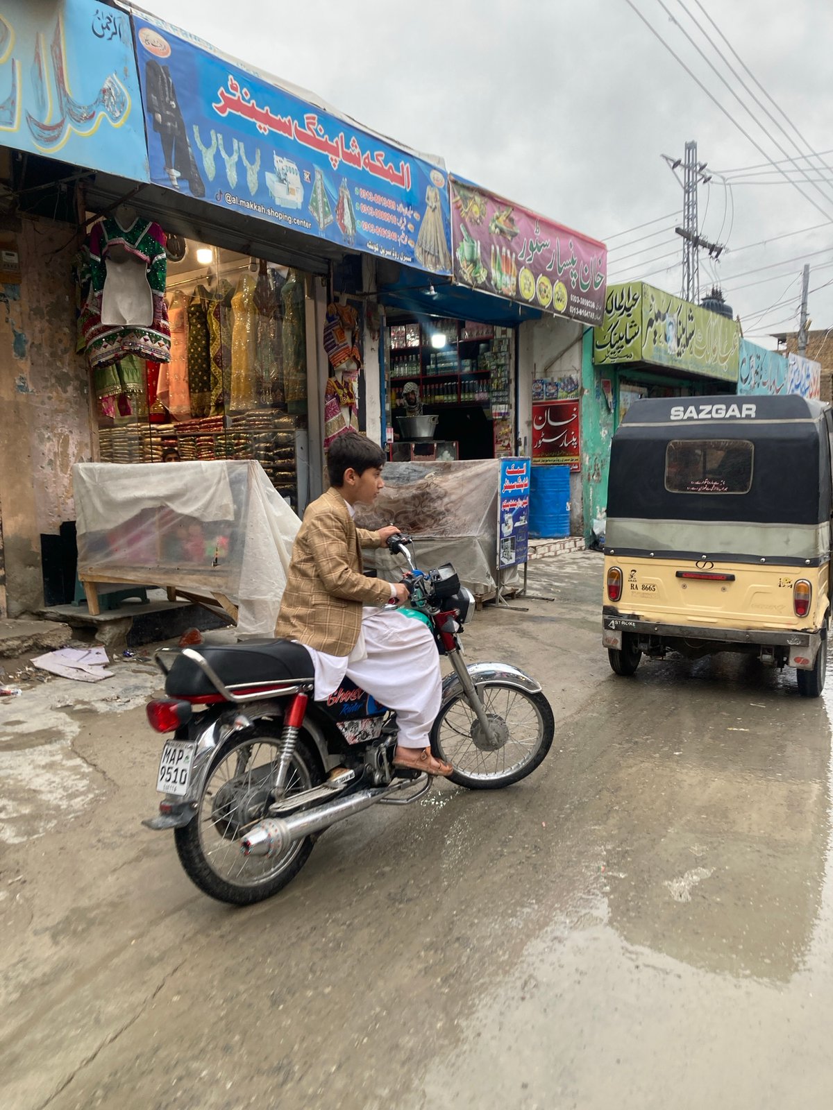 Boy sits on motorcycle near shop in Quetta