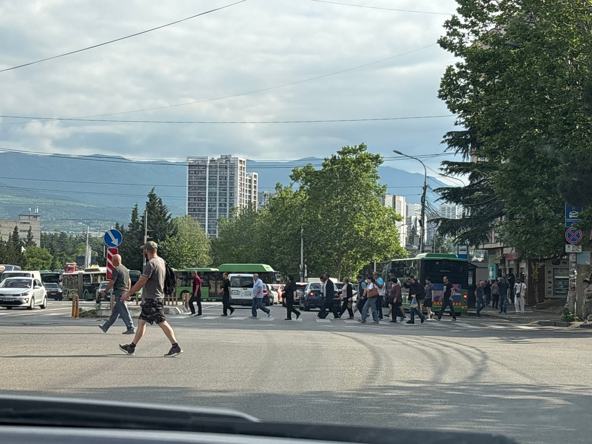 Tbilisi intersection buzzing with traffic and pedestrians on a cloudy morning