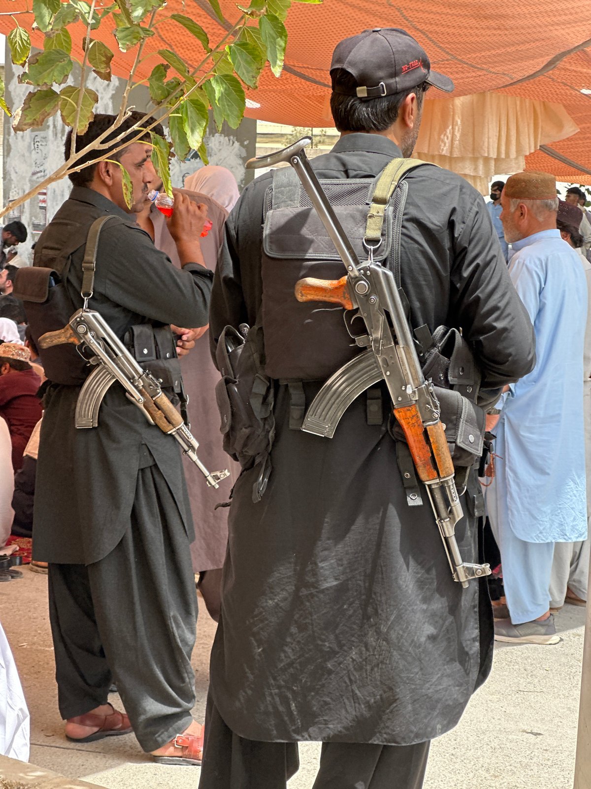 Armed figures and a seated gathering in Quetta, Pakistan