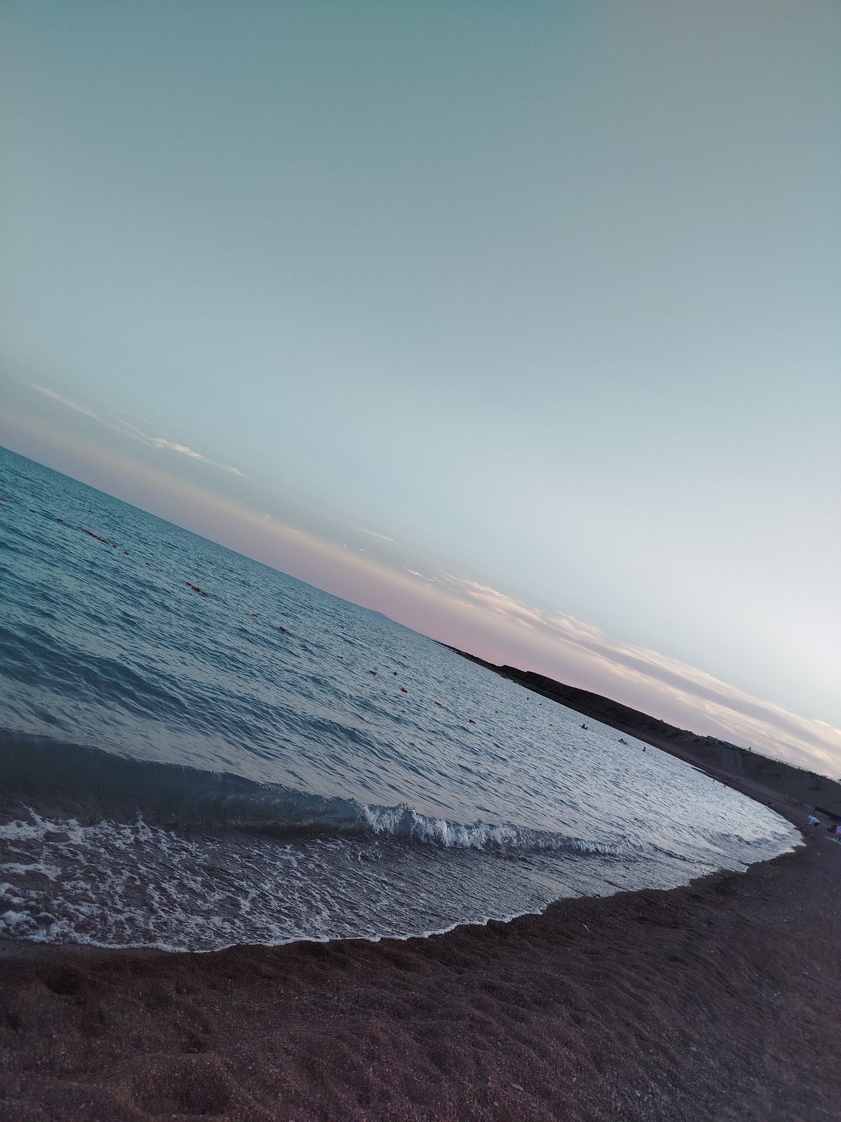 Quiet beach at golden hour, calm water and scattered people