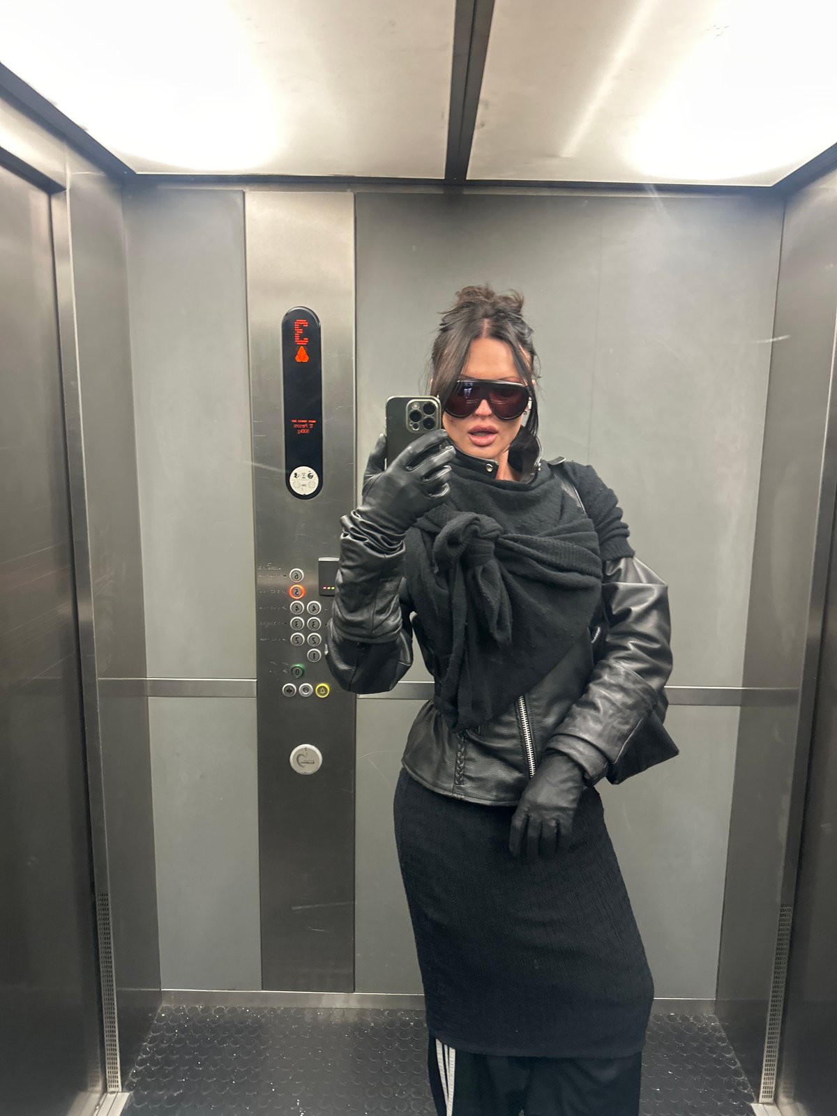 Person travels through London Underground wearing dark clothing, sunglasses