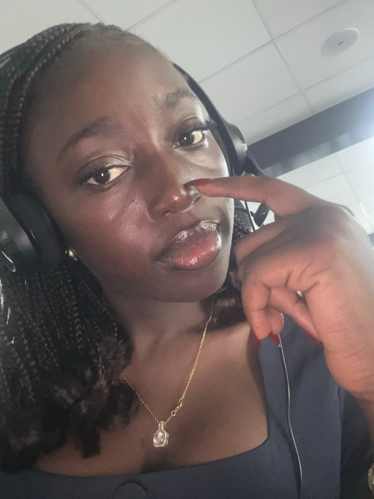 Woman with headphones touches nose indoors in Karum, Nigeria