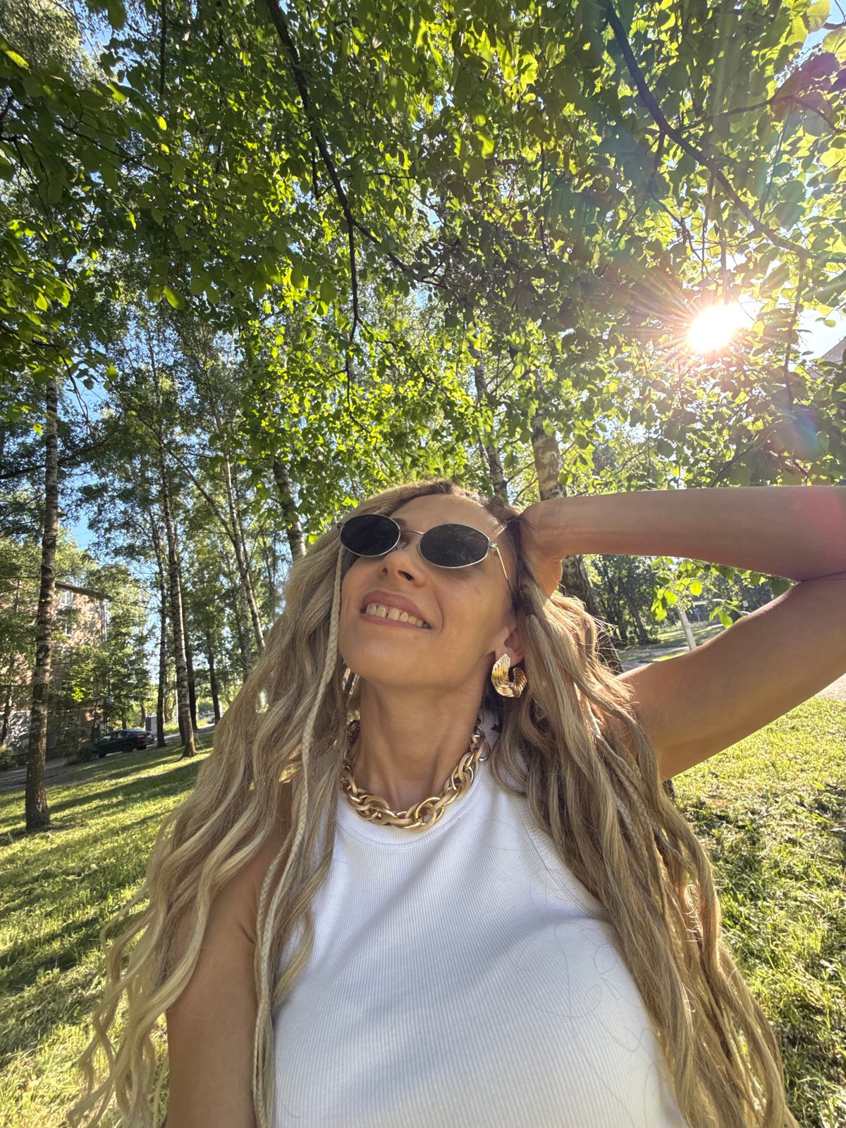 Woman in gold jewelry takes outdoor selfie