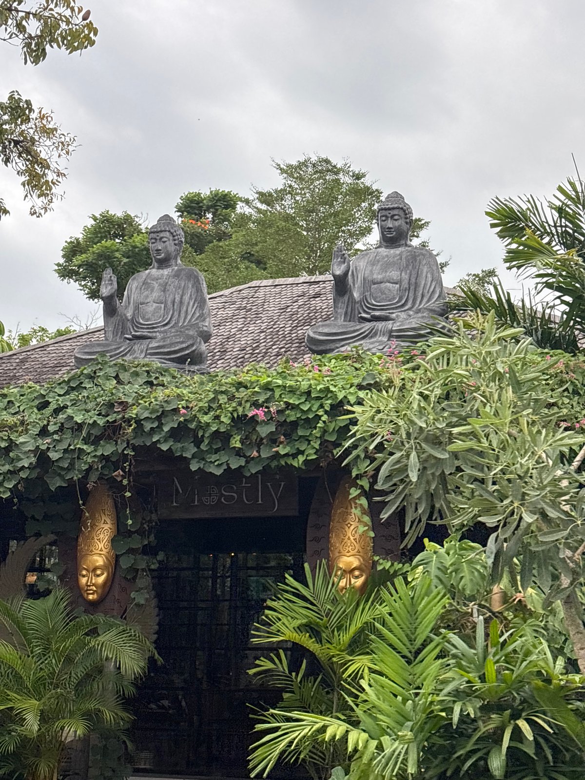 Buddha statues mark ivy-covered entrance in Mengwi, Indonesia