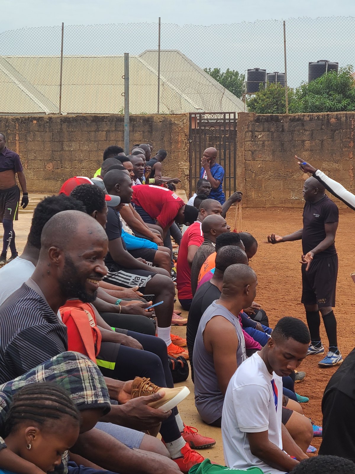 Groups gather for morning athletic activities on urban dirt fields