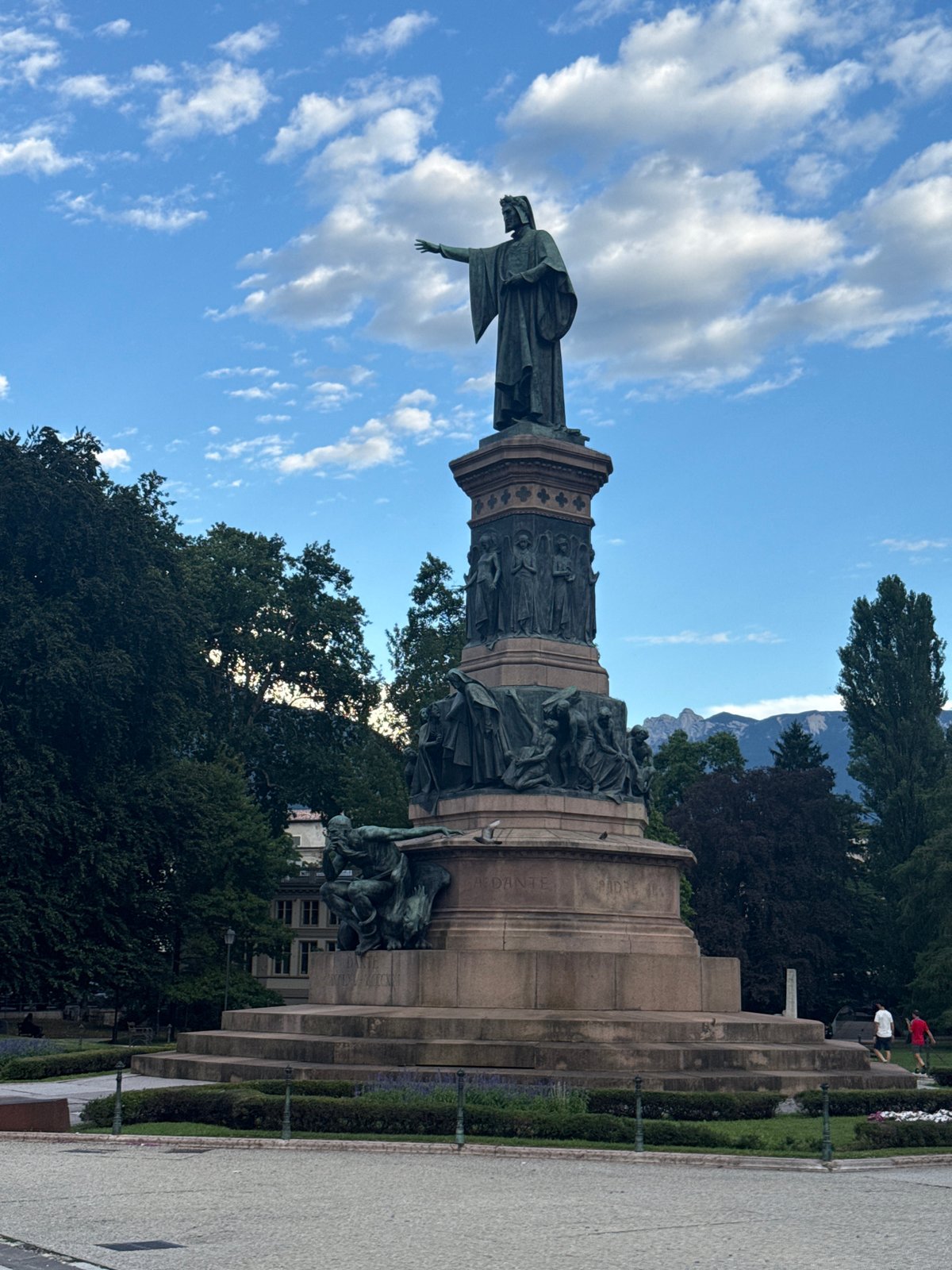 Bronze monument with robed figure, Trento's open sky behind it