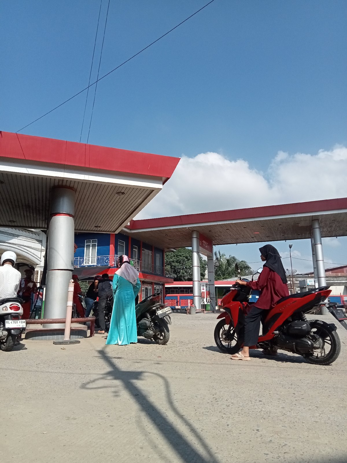 Morning scooter traffic at a rural Indonesian gas station