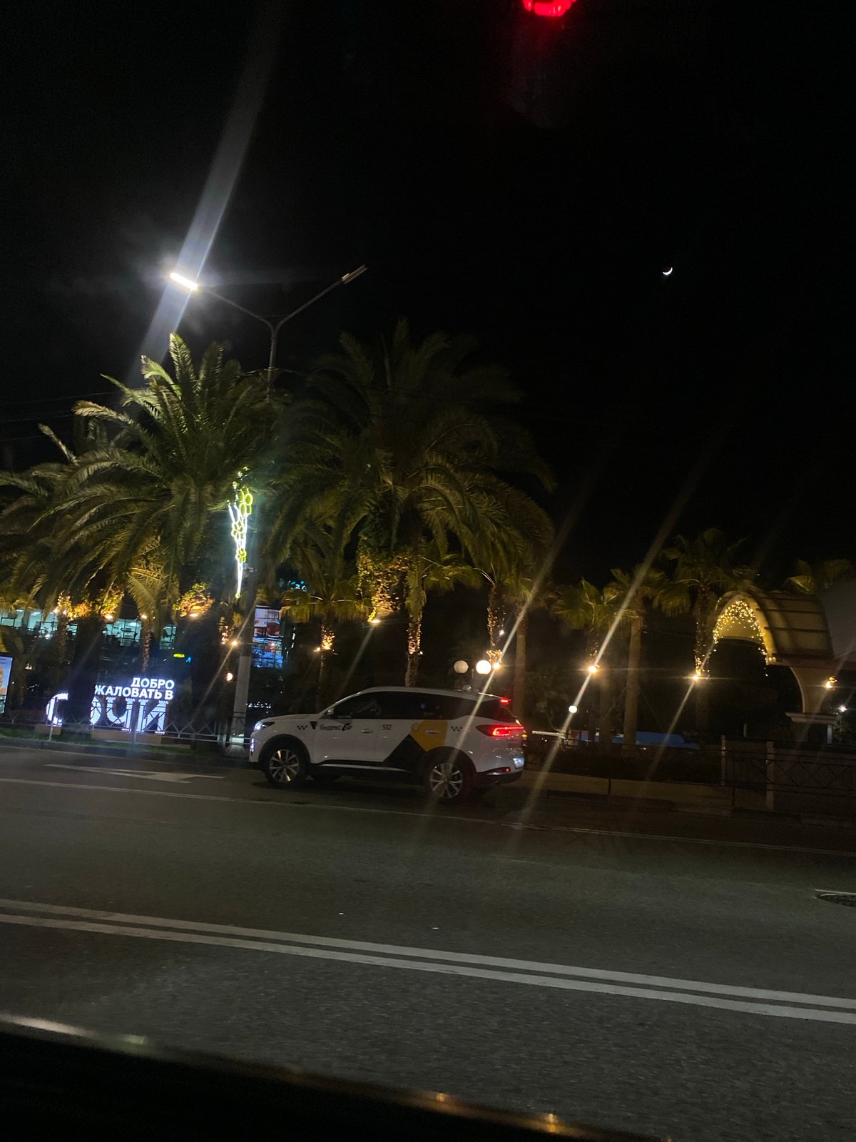 Nighttime street scene captured in Sochi under crescent moon