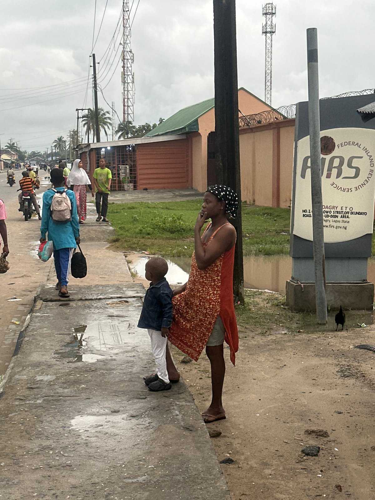 Morning foot traffic through Badagry streets under heavy cloud cover