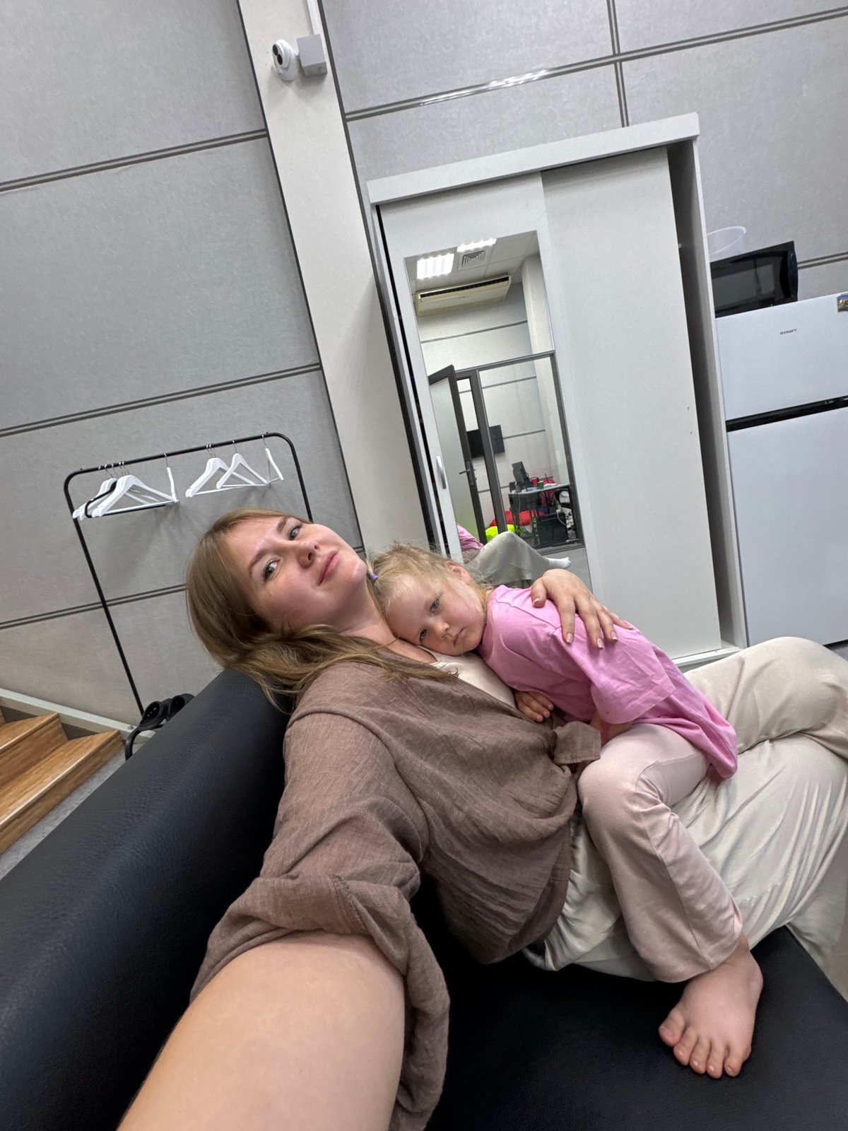 Mother holds sleeping toddler on couch in Perm home