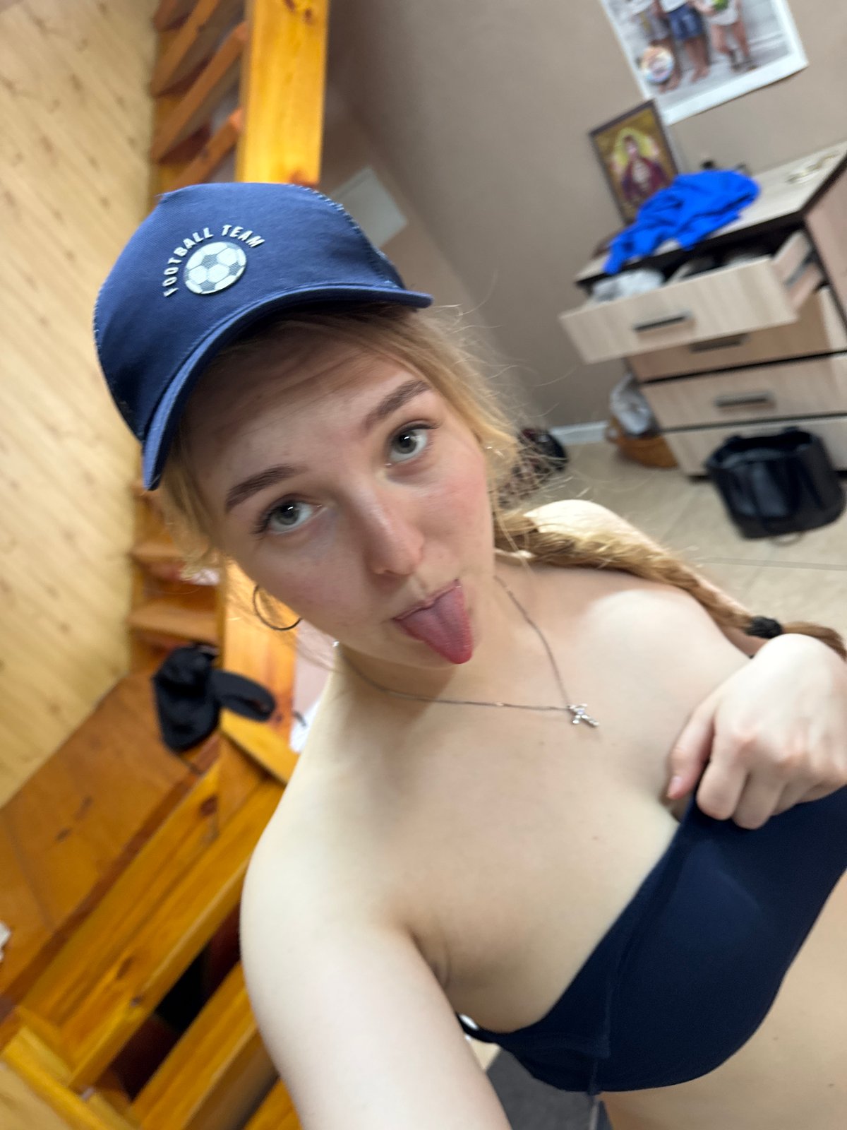 Women take playful mirror selfies, one wearing soccer cap