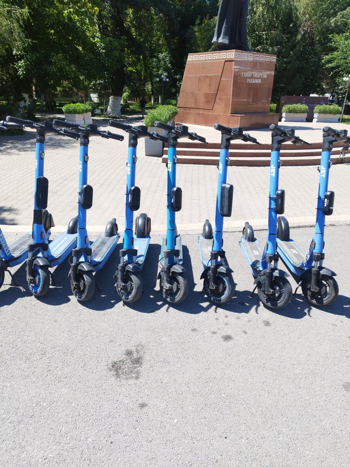 Electric scooters and monuments at a Shymkent civic plaza