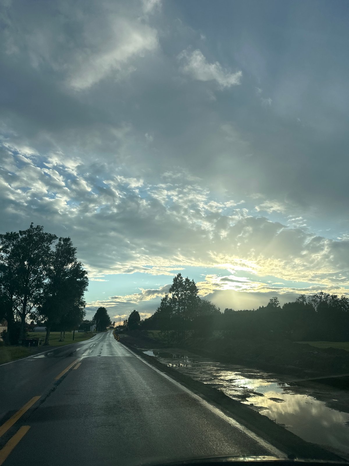 Rainy drive down a quiet rural road under stormy skies