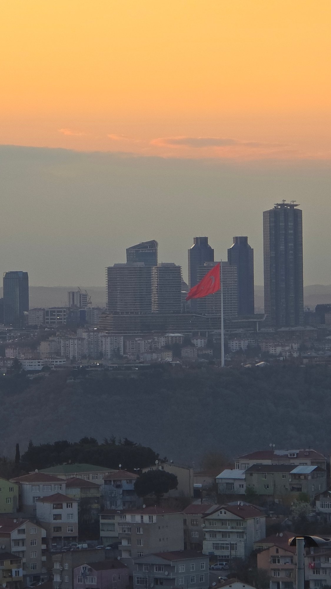 Turkish flag prominently displayed over Üsküdar skyline at dusk