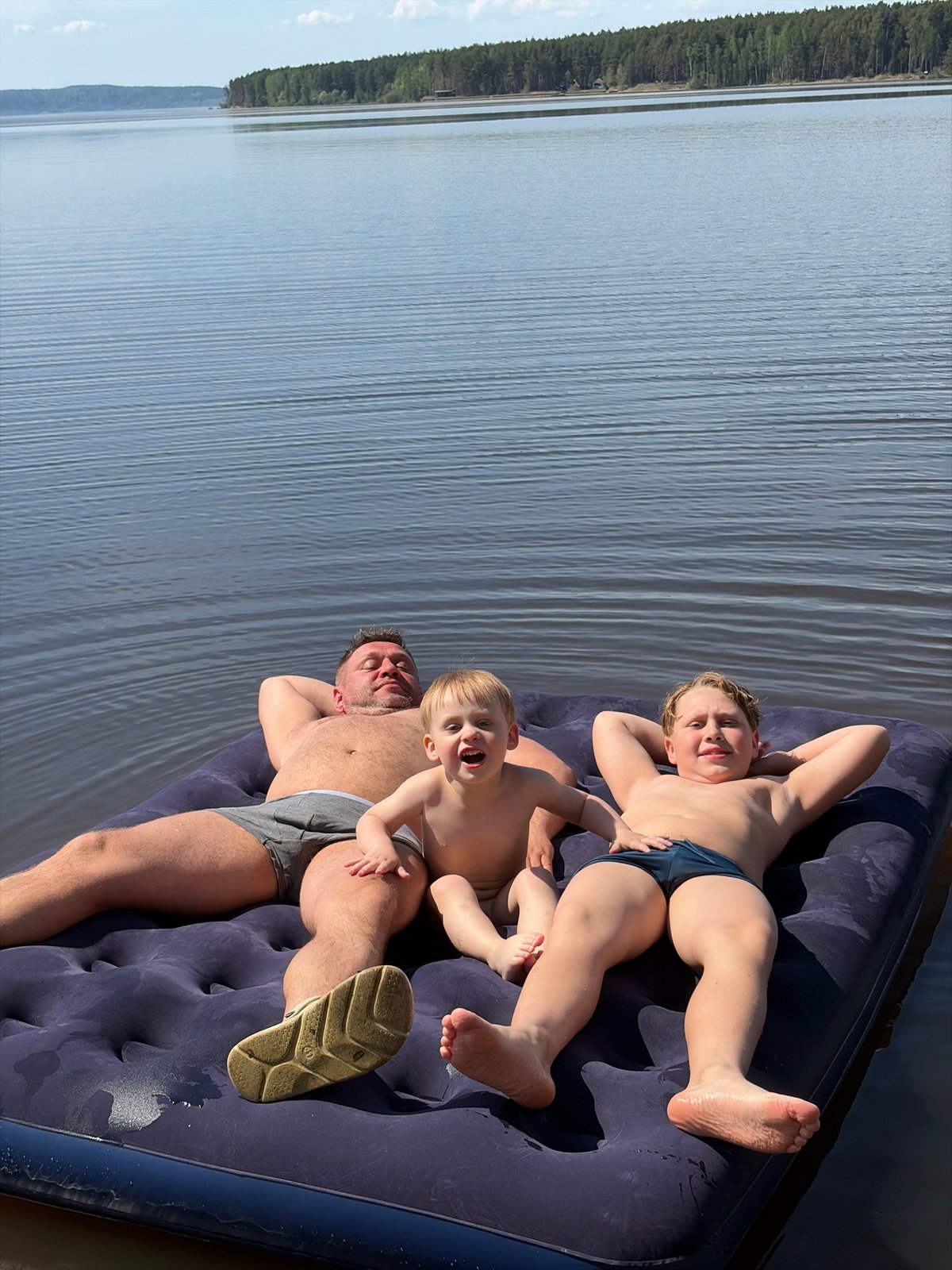 Family enjoys water recreation on inflatable mattress in Russia