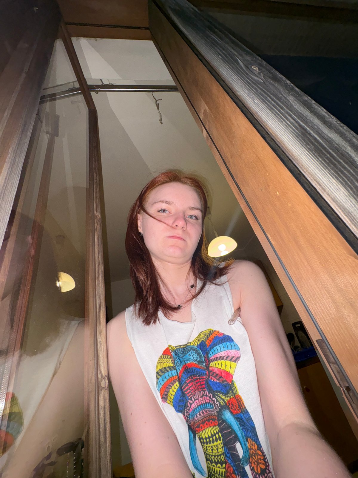 Red-haired person in white shirt photographed frowning at camera