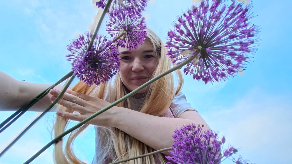 Woman poses with purple flowers during outdoor photoshoot in Russia