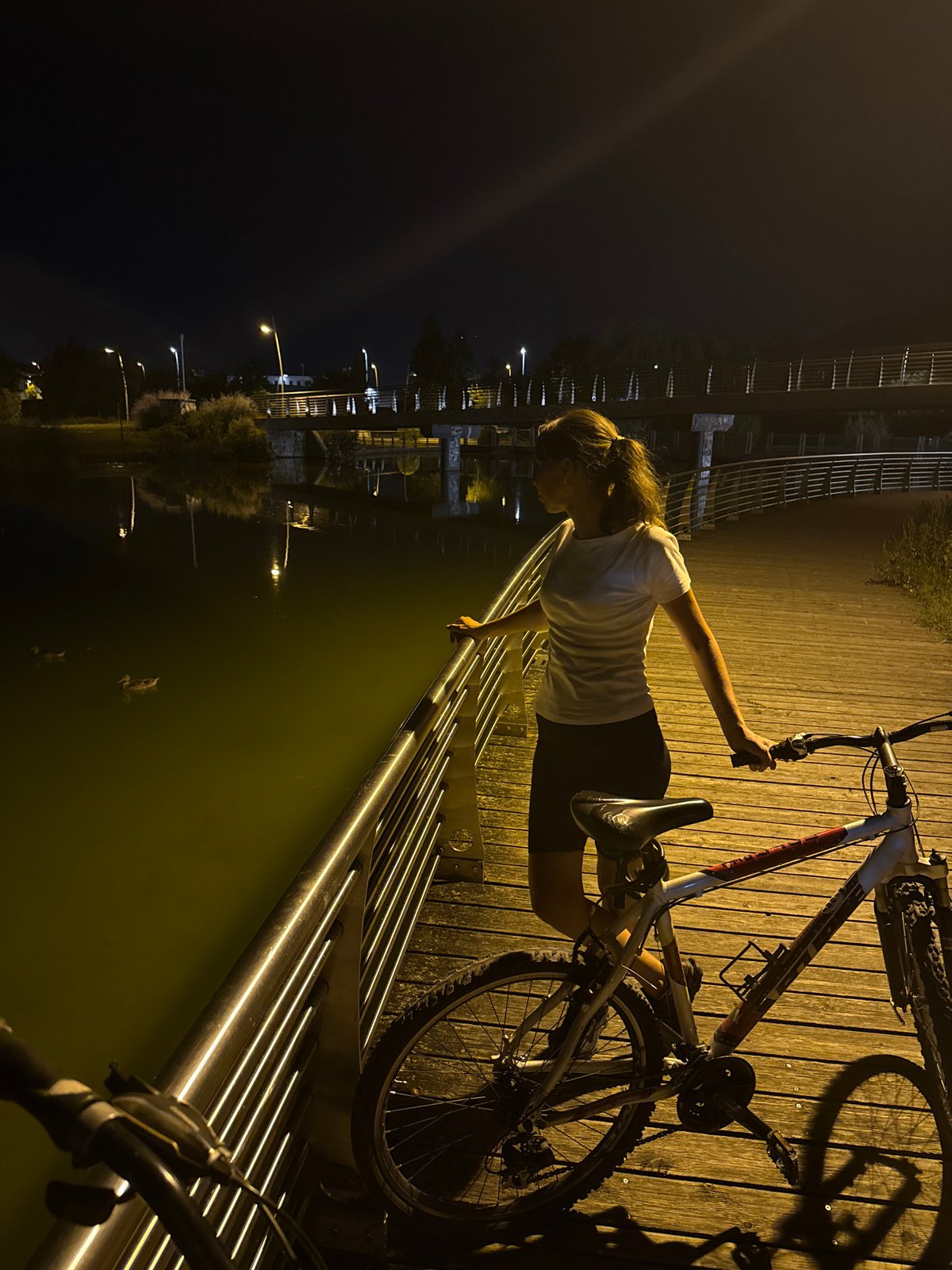Night cycling along Trento's lit waterfront boardwalk