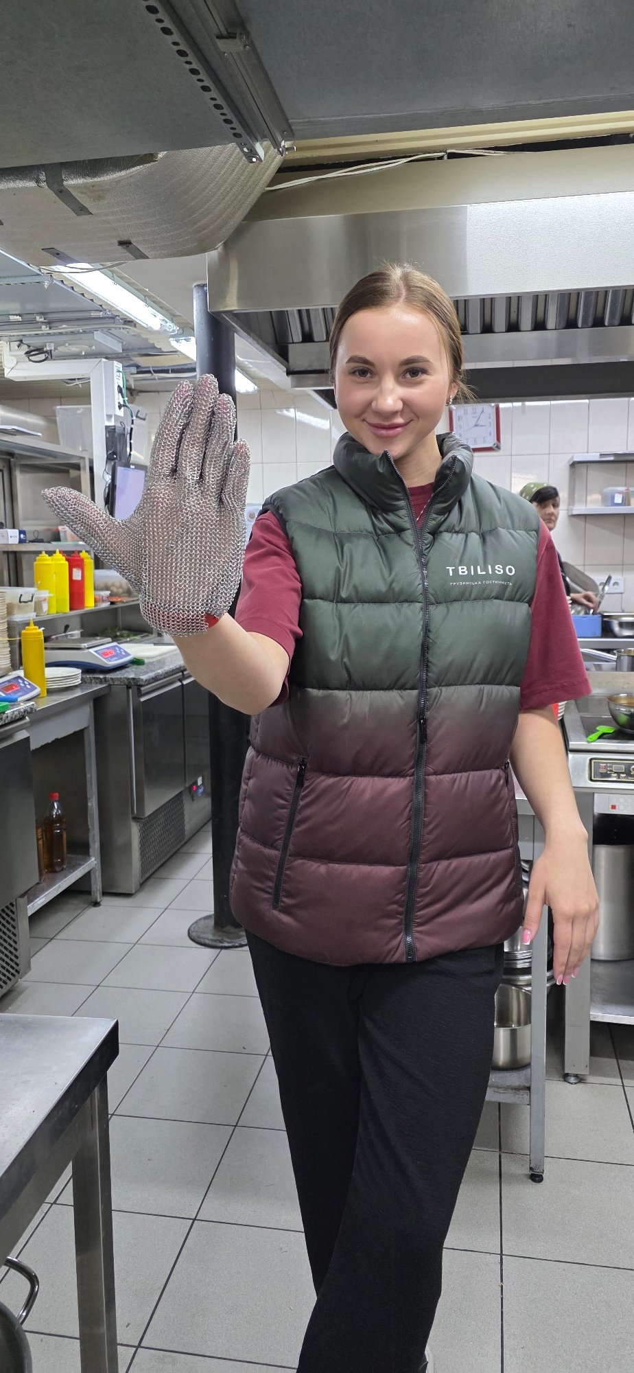 Woman displays metal mesh glove in Ukrainian commercial kitchen