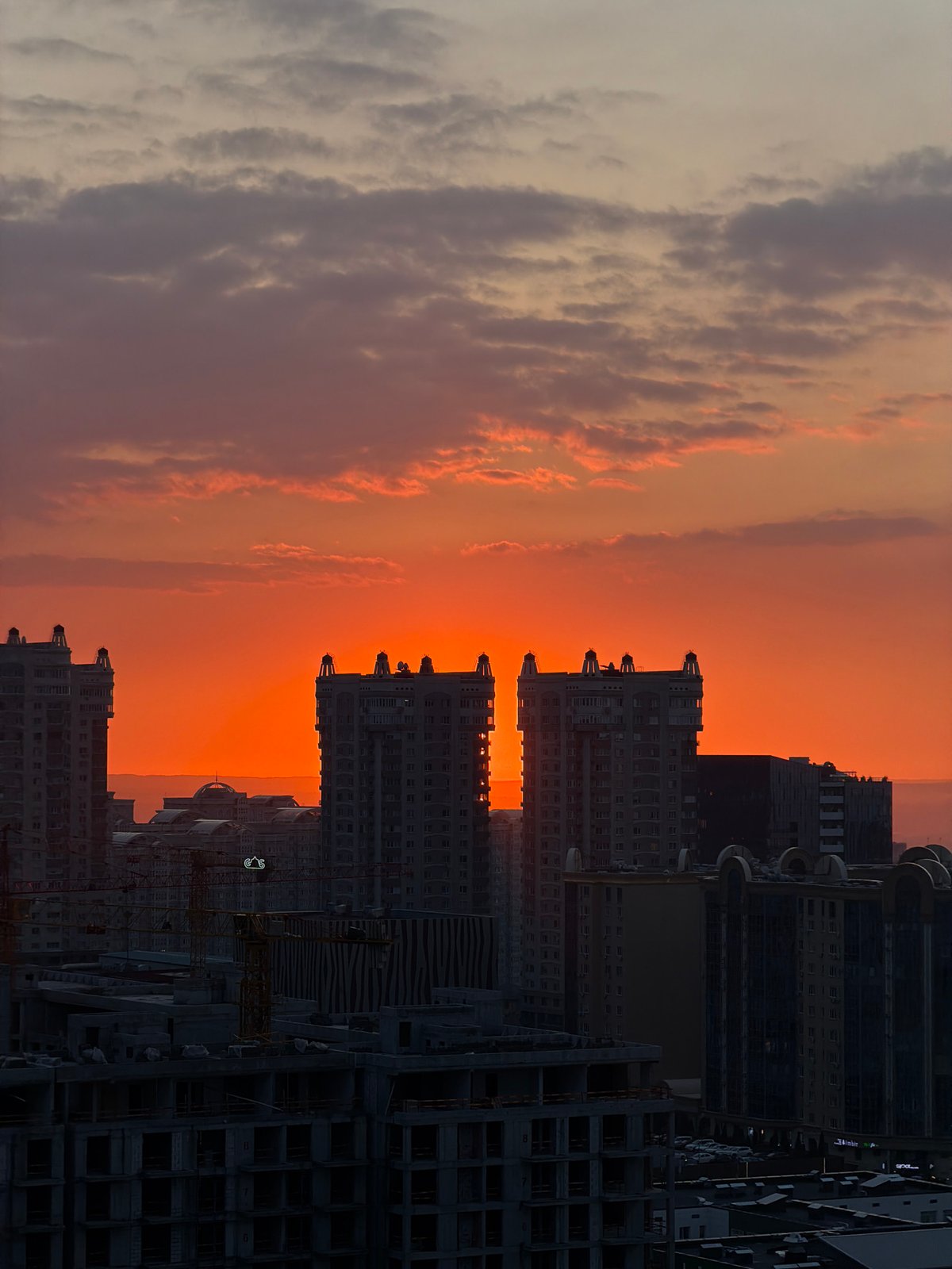 Almaty skyline photographed against orange sunset sky