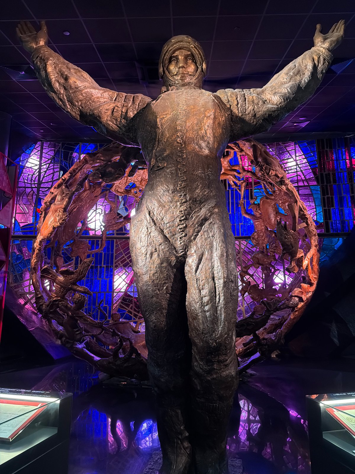 Bronze cosmonaut statue reaches upward before stained-glass window in Moscow