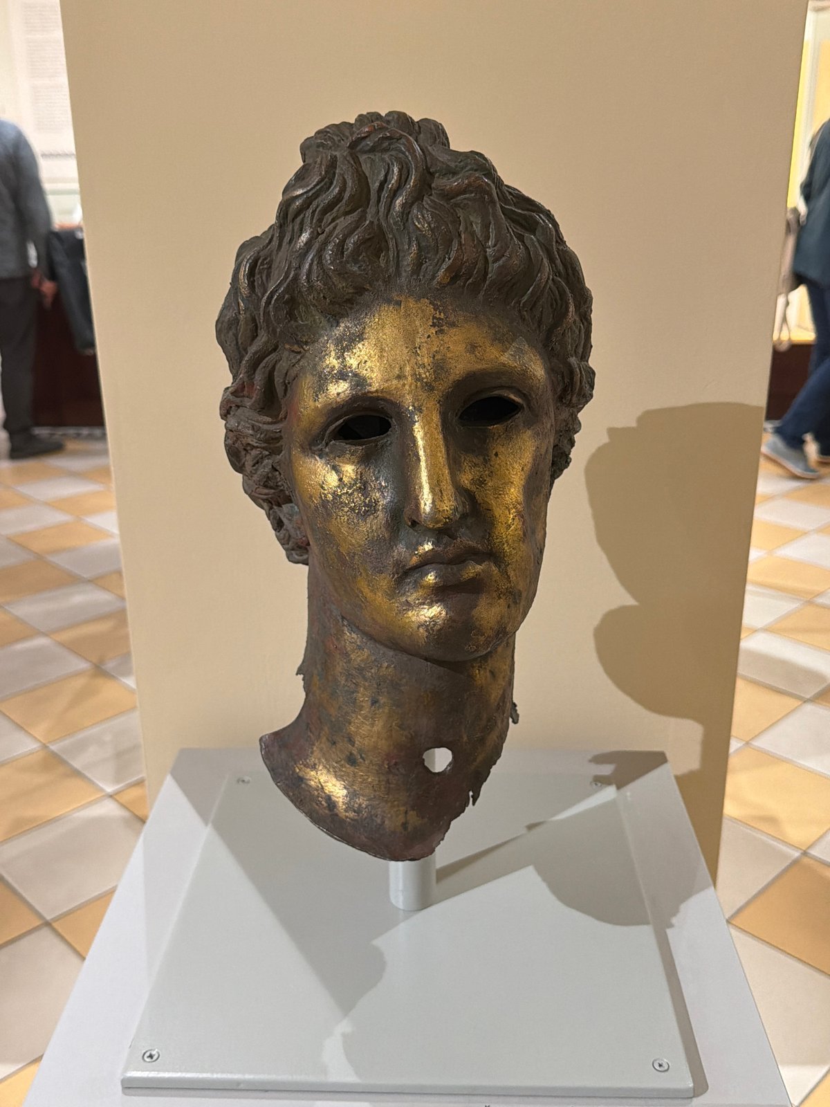 Museum visitor documents bronze sculpture and ancient dwelling exhibits