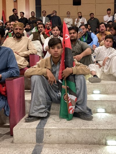 South Asian men gather in auditorium for indoor meeting