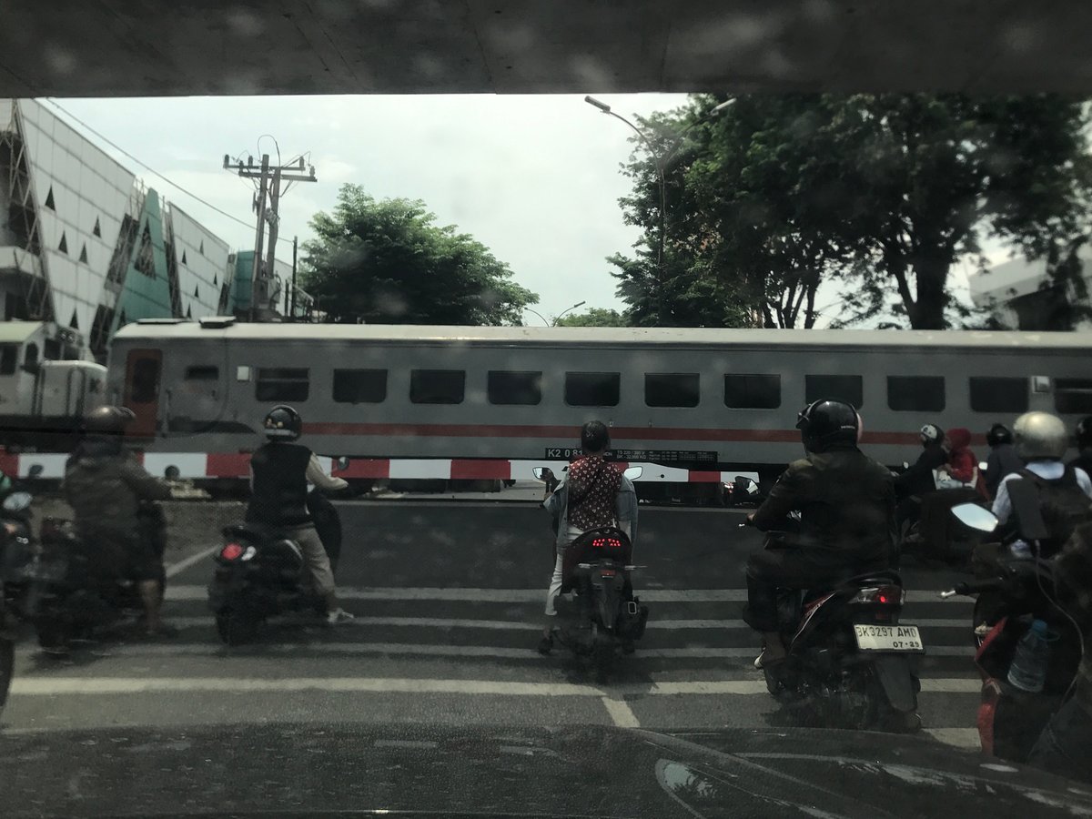 Motorbikes wait at crossing as train passes through Medan