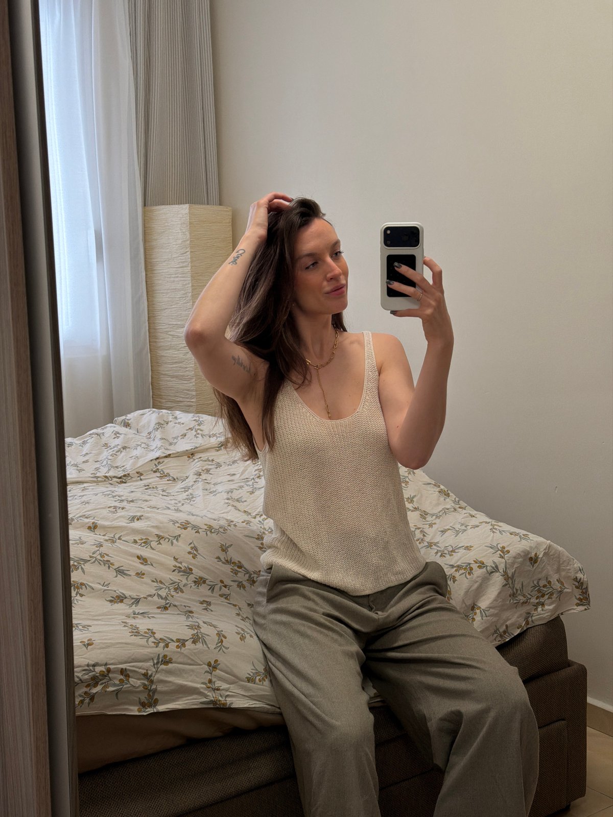 Woman takes mirror selfie on bed in Budva