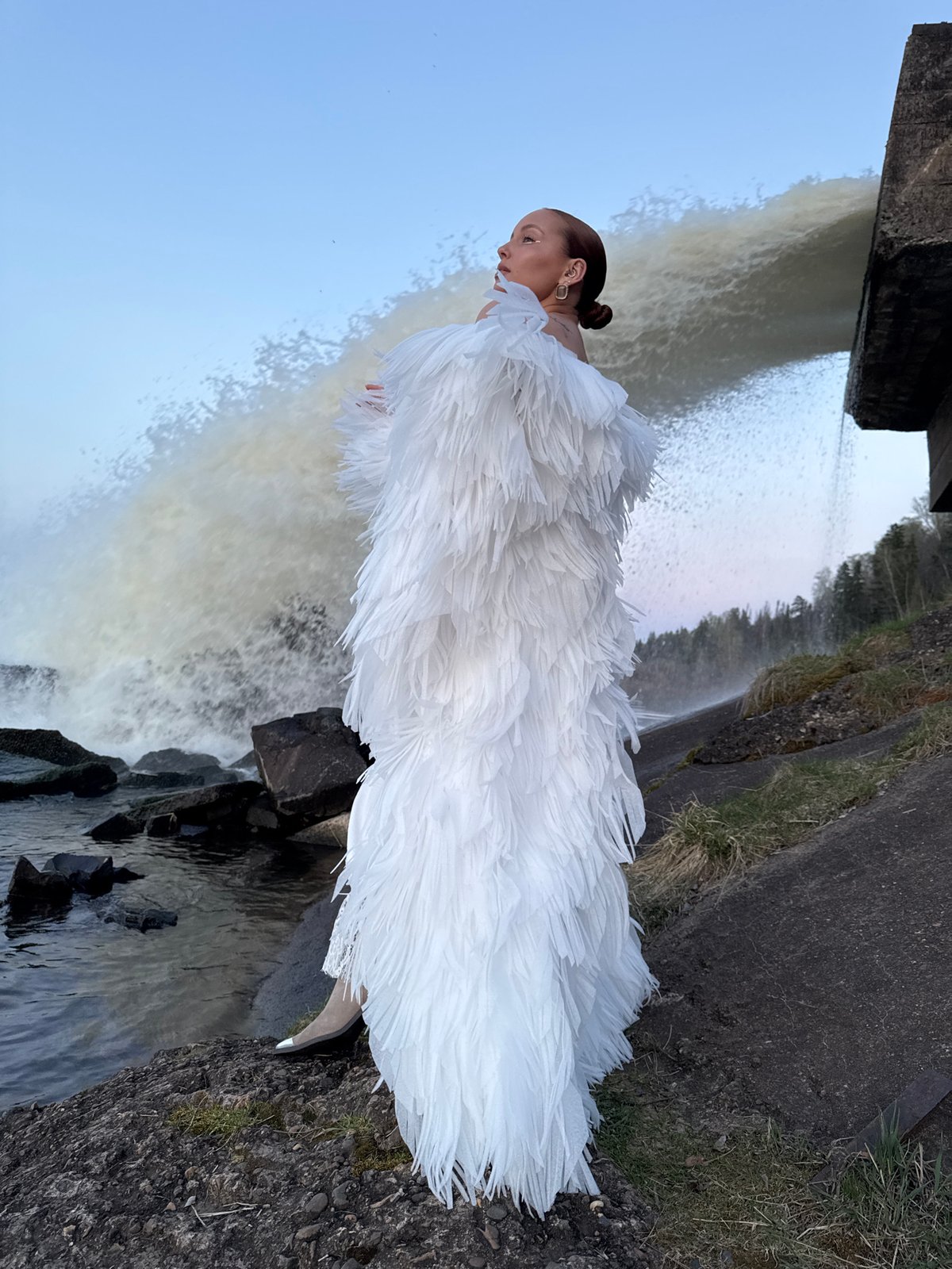 Woman poses in white dress near Chernushka Dam waterfall