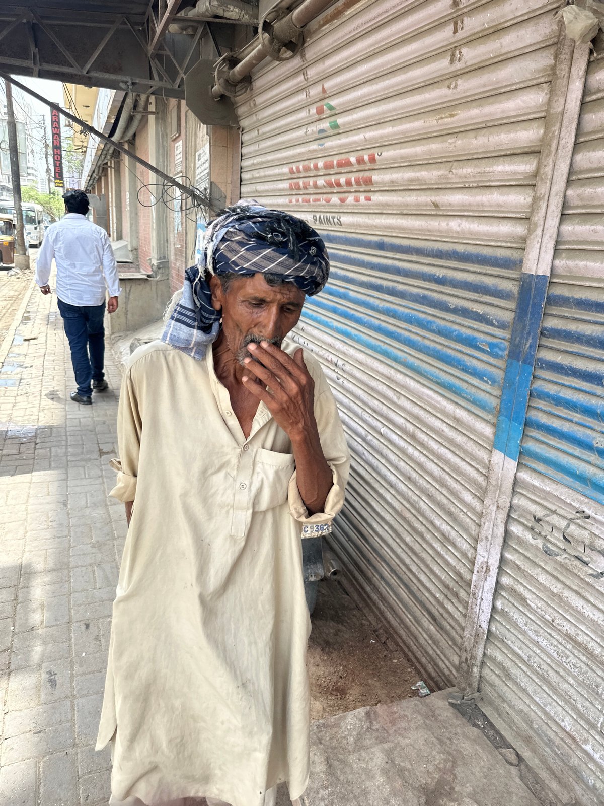 Morning street activity near a Karachi storefront, donkey cart in tow