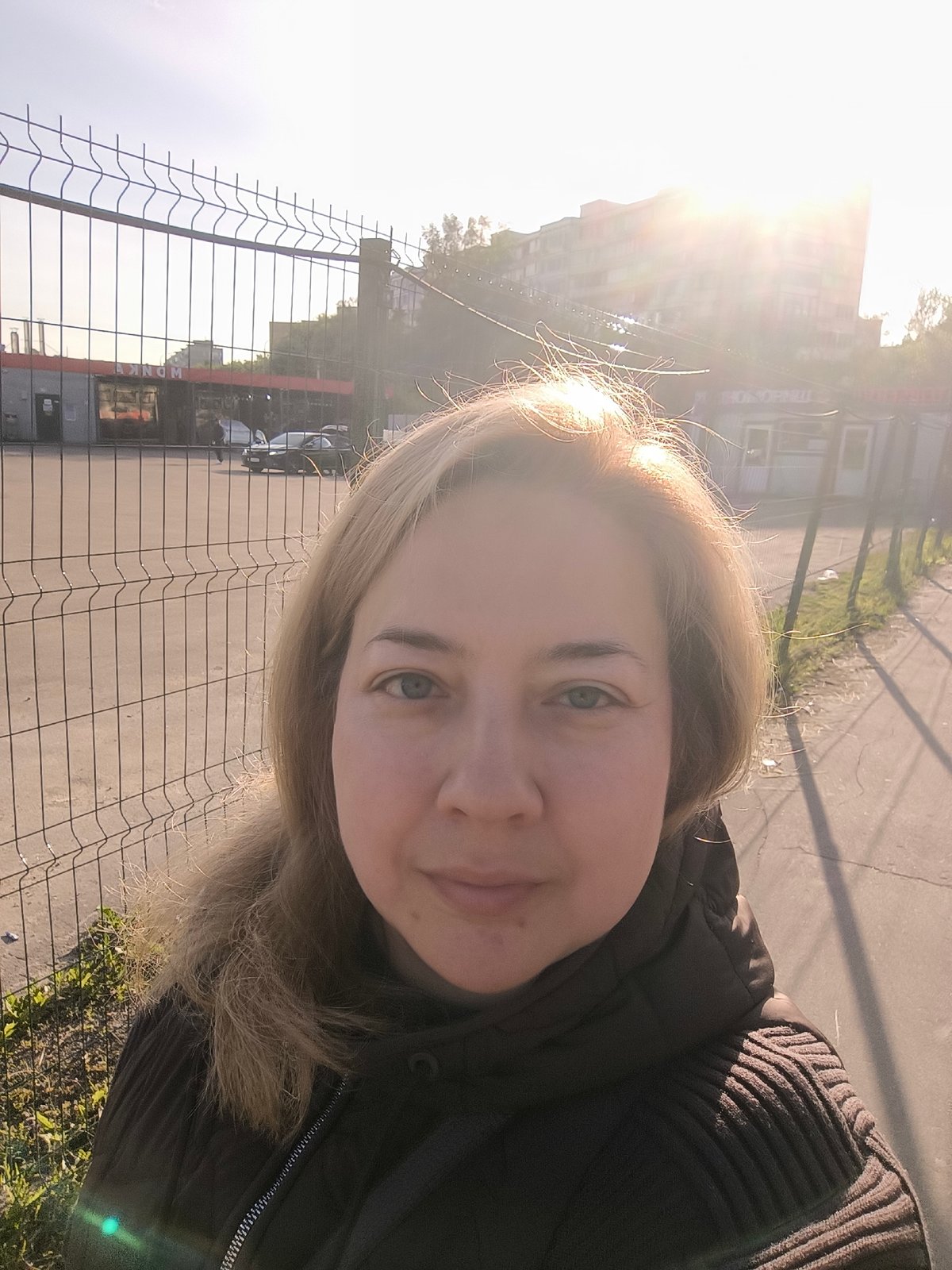 Woman photographed at fence and subway with Russian signage
